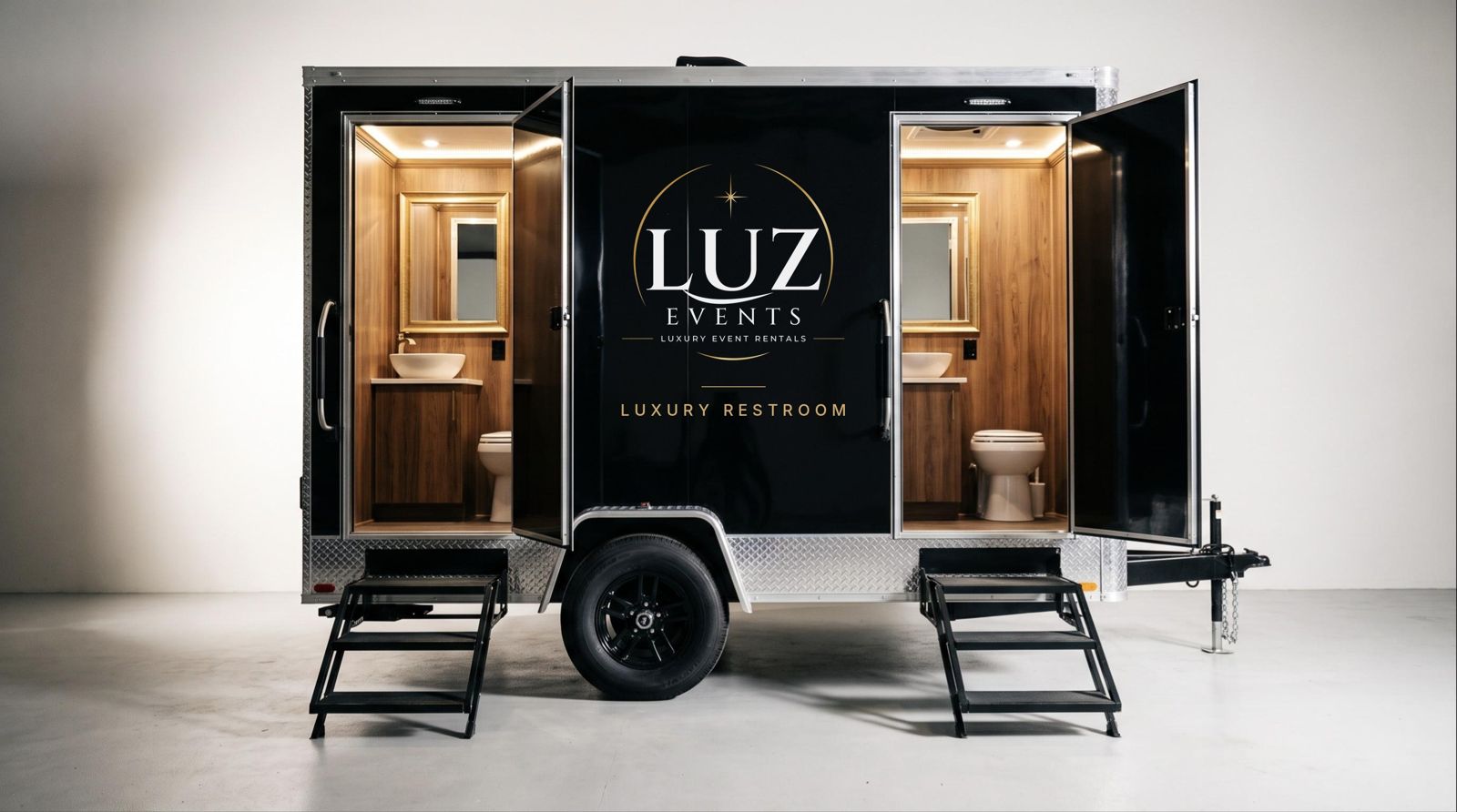 The Luz Suite — black luxury restroom trailer with two private wood-finish suites, vessel sinks and gold-framed mirrors